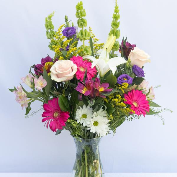 Mixed bouquet of pink, white, purple, and yellow flowers in a glass vase