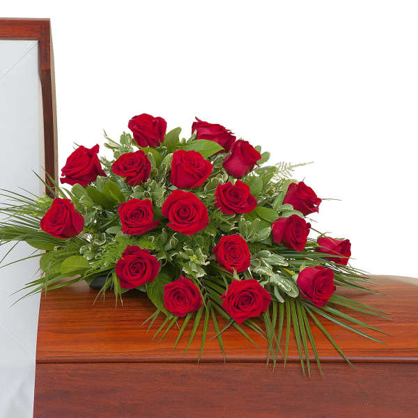 Red rose casket spray arranged on a closed wooden casket