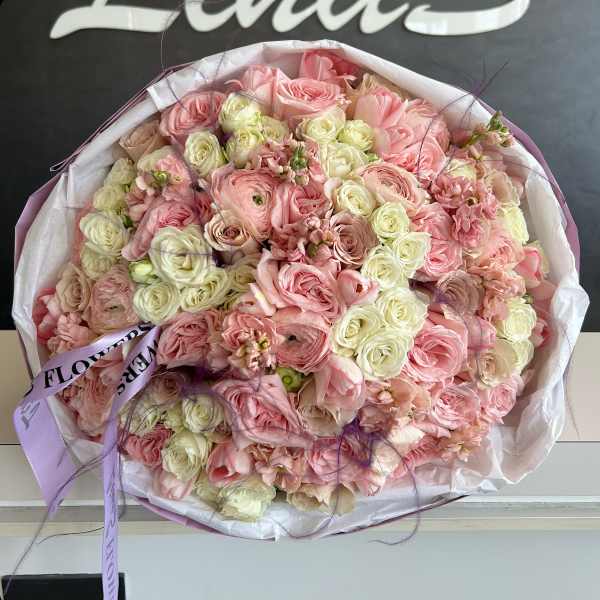 Large bouquet of pink and cream roses wrapped in white paper