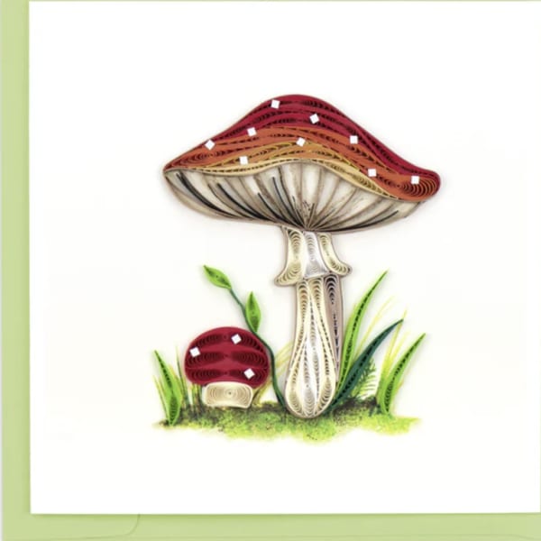 Quilled paper illustration of two red mushrooms with grass on a white greeting card.