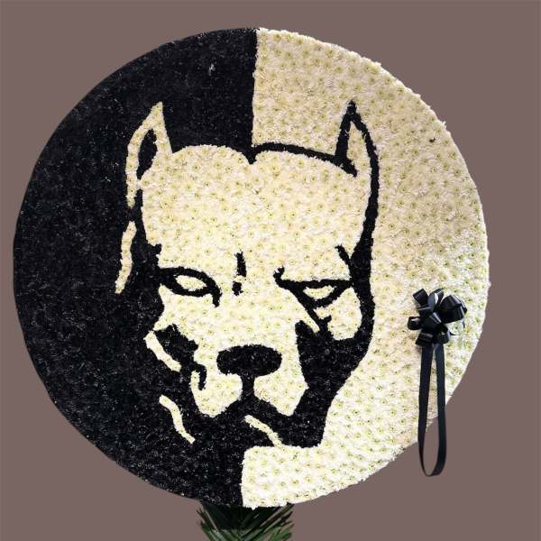 Round floral tribute with a black-and-white dog face design and ribbon accents