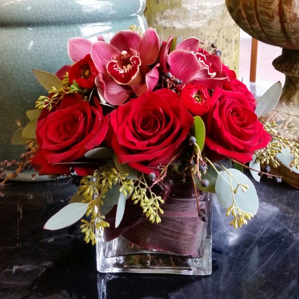 Red roses and pink orchids in a square glass vase