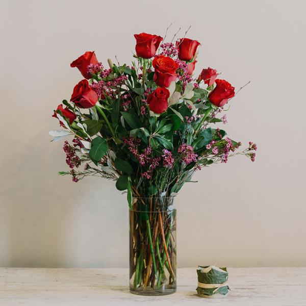 Red roses in a clear glass vase with small pink filler flowers