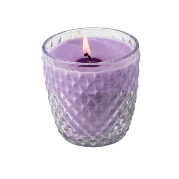 Lit lavender candle in a textured clear glass holder against a white background