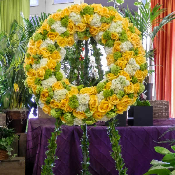 Large yellow and white floral wreath on a stand