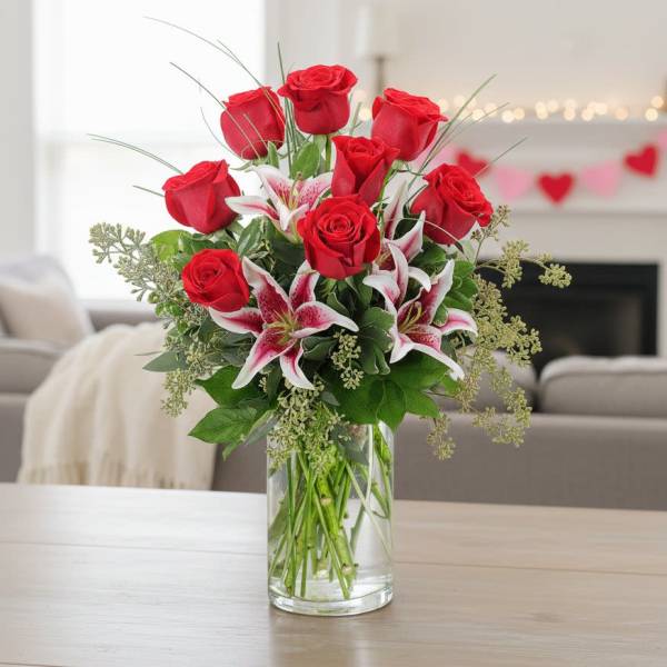 Arrangement of red roses and pink lilies in a clear glass vase on a table