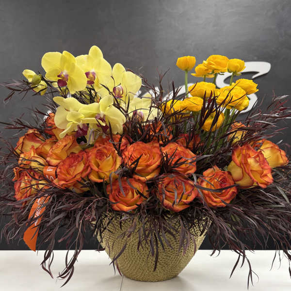 Orange roses and yellow orchids in a woven basket