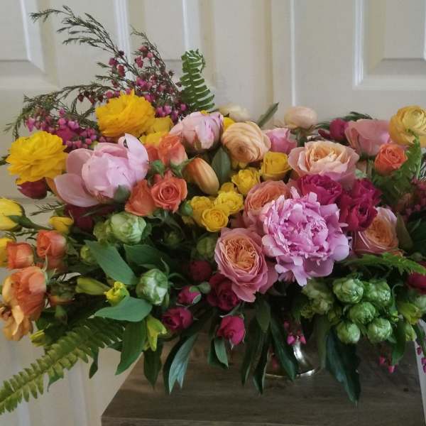 Large bouquet of pink, yellow, and peach flowers in a vase