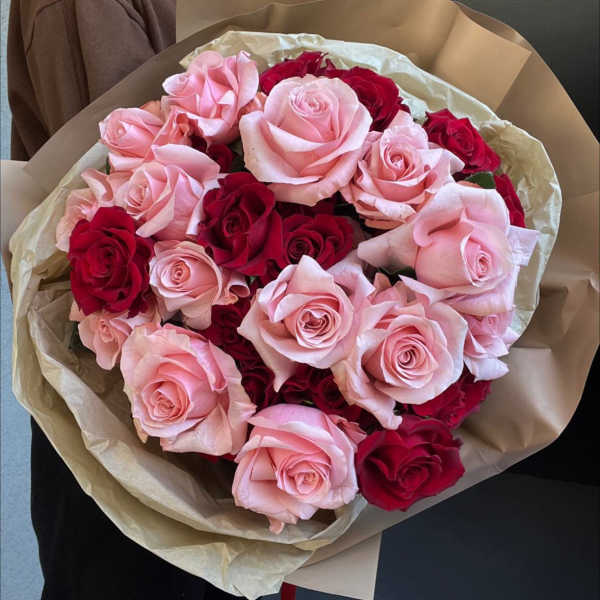 Bouquet of pink and red roses wrapped in tan paper