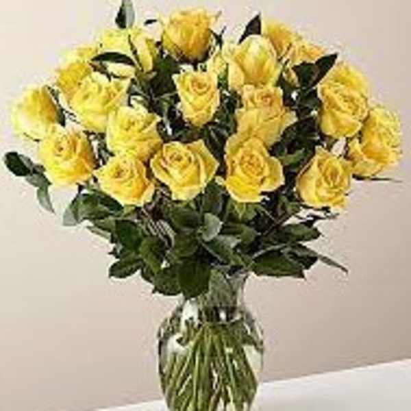 Large bouquet of yellow roses arranged in a clear glass vase
