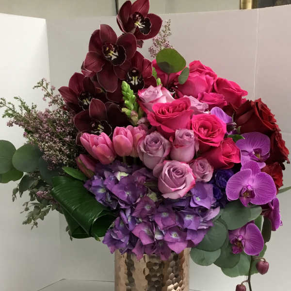 Bouquet of pink, purple, and burgundy flowers in a glass vase
