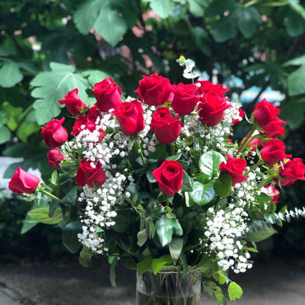 Bouquet of red roses and white baby's breath in a glass vase