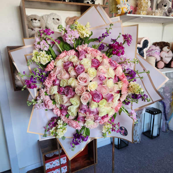 Large bouquet of pink, cream, and purple roses with ruffled blooms