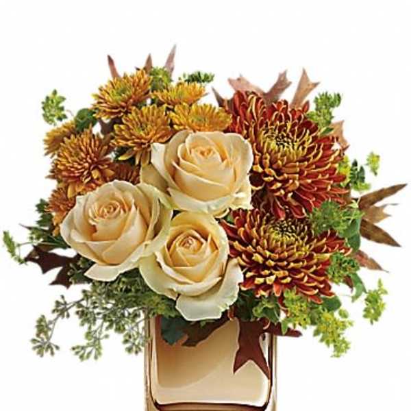 Cream roses and autumn chrysanthemums in a clear glass vase