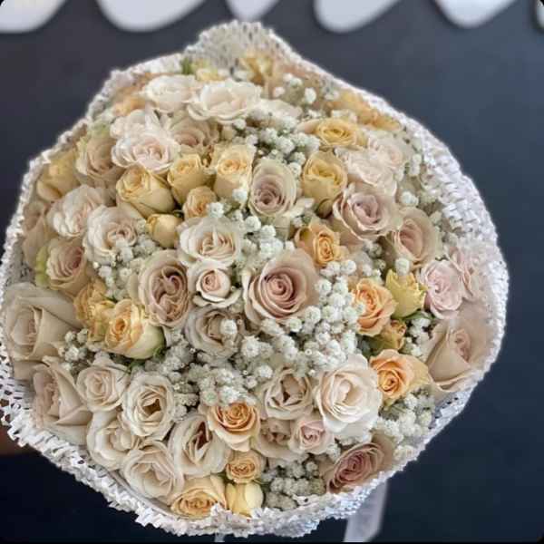 Round bouquet of cream and blush roses with white filler flowers