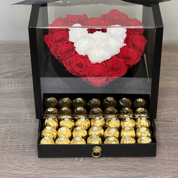 Black display box with a heart of red and white roses above a drawer of gold-wrapped chocolates