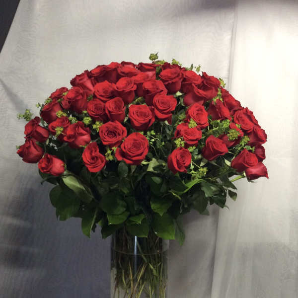 Large arrangement of red roses in a tall clear glass vase