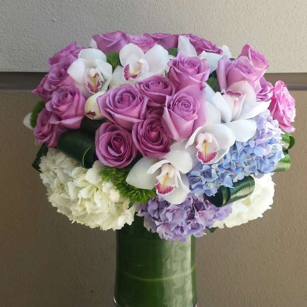 Pink roses and white orchids arranged with hydrangeas in a glass vase