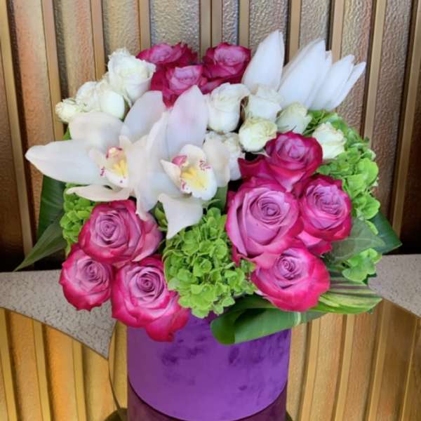 Pink and white roses with white orchids in a purple vase