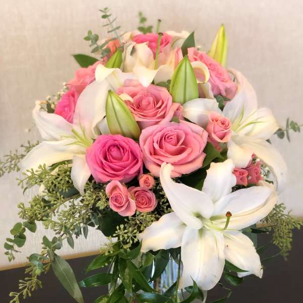 Pink roses and white lilies arranged in a glass vase
