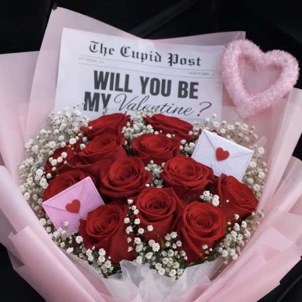 Bouquet of red roses with baby’s breath, pink wrap, and Valentine card