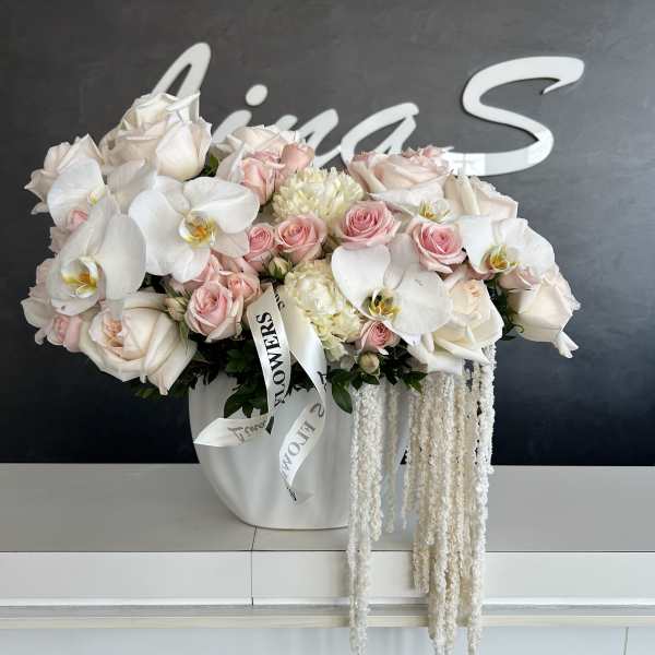 White and blush bouquet of roses and orchids in a white vase