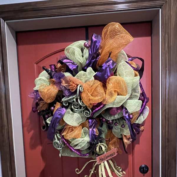 Halloween wreath with purple, orange, and green mesh on a red door
