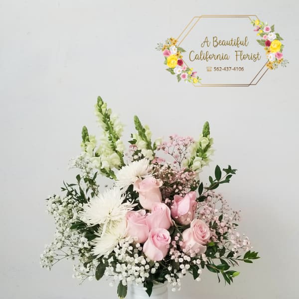 Pink roses and white flowers arranged in a white vase