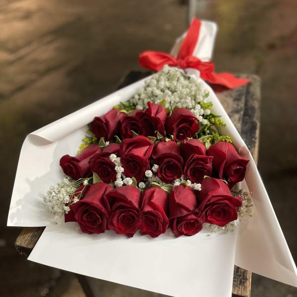 Bouquet of red roses wrapped in white paper with a red ribbon