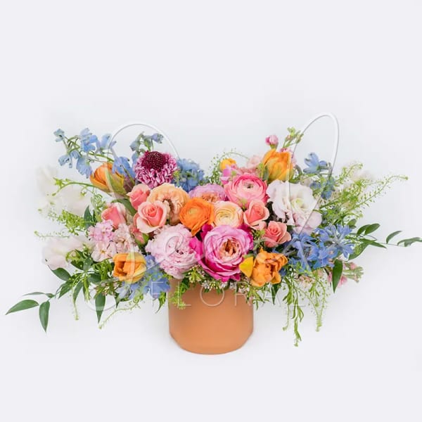 Mixed bouquet of pastel flowers in a tan vase