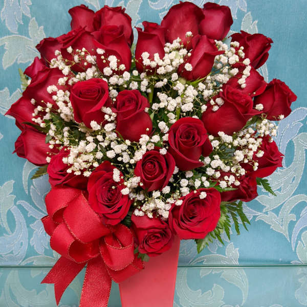 Red roses with white baby's breath in a pink vase and ribbon
