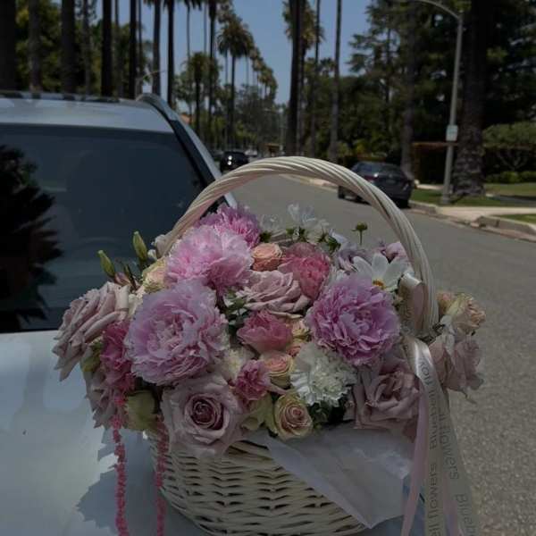 Pink and lavender flower basket with roses and peonies on a car hood