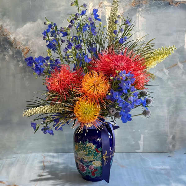 Colorful floral arrangement in a blue vase with a ribbon