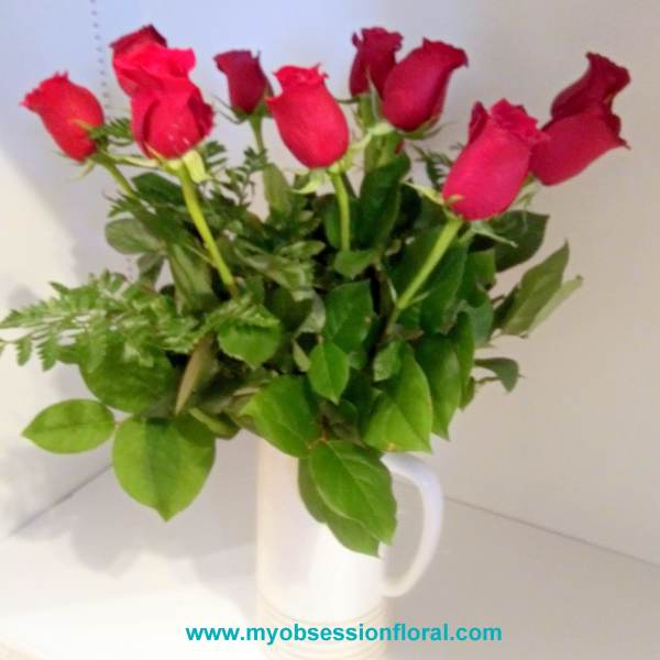 Red roses in white pitcher.