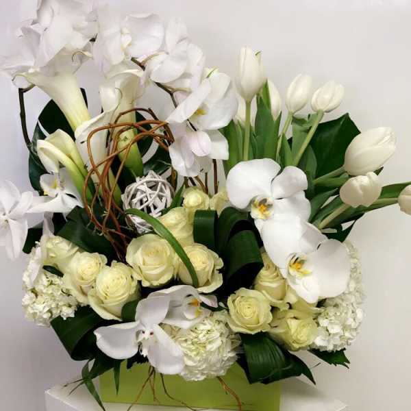 White orchids, roses, and tulips arranged in a green box