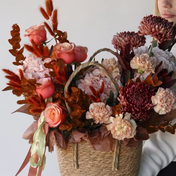 Basket arrangement of pink roses and burgundy chrysanthemums