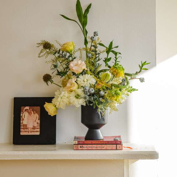 Mixed floral arrangement in a black vase with yellow and white blooms