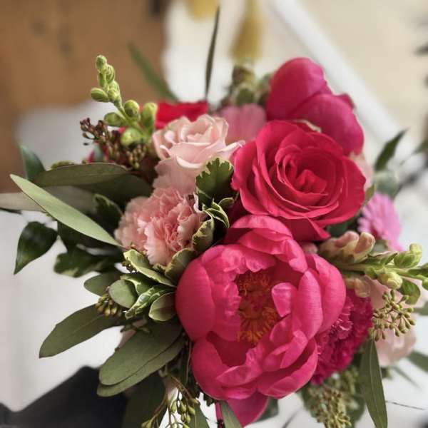 Handheld bouquet of hot pink peonies and pale pink roses