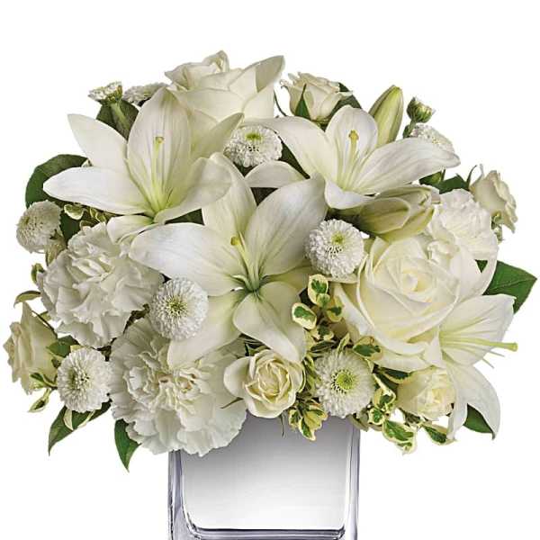 White lilies and roses arranged in a clear glass vase
