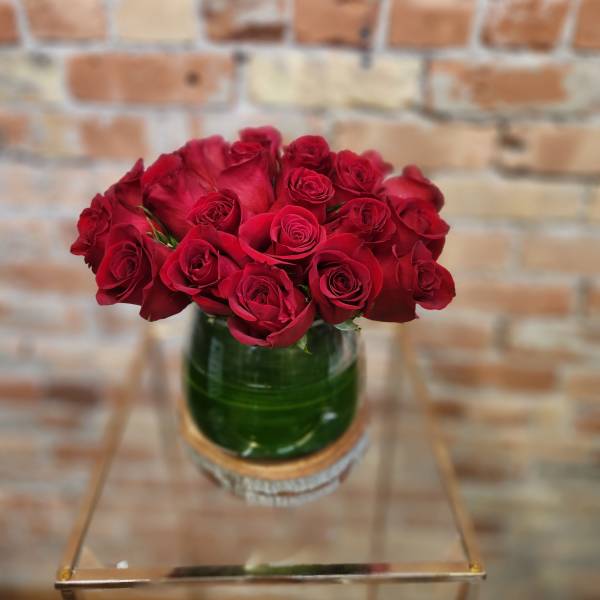 Red roses arranged in a green glass vase