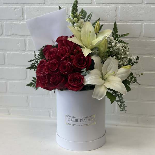 Red roses and white lilies arranged in a white hat box