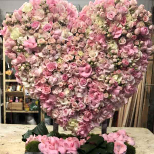 Heart-shaped pink floral arrangement on a rectangular base