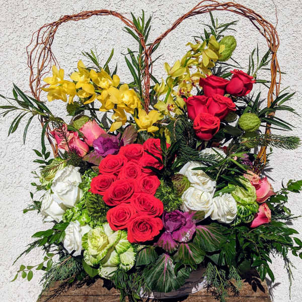 Heart-shaped floral arrangement with red, white, pink, and yellow roses
