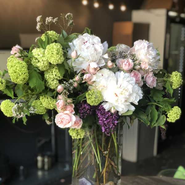Mixed bouquet of white and pink flowers in a tall glass vase