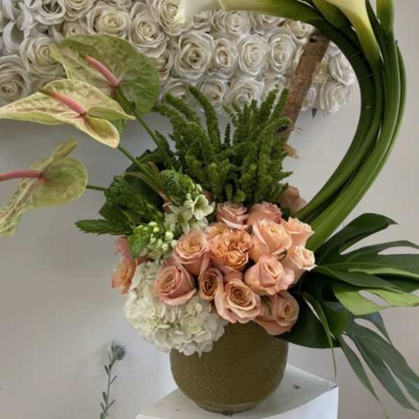 Floral arrangement with white roses, peach roses, calla lilies, and anthuriums in a vase