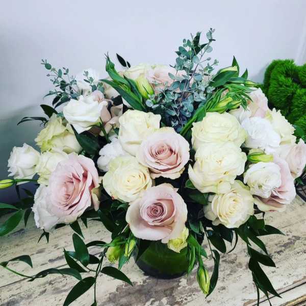 Bouquet of pale pink and white roses in a dark vase