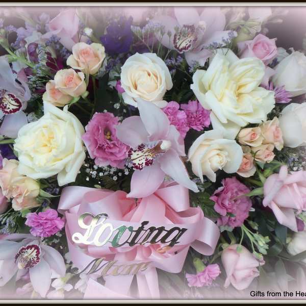 Pink and white floral arrangement with a pink ribbon and "Loving Mom" sign