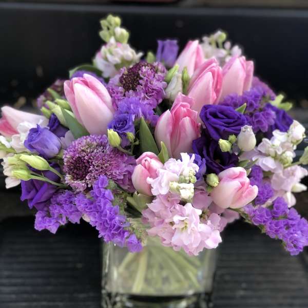 Pink and purple bouquet in a clear square vase