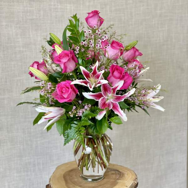 Pink roses and lilies arranged in a clear glass vase