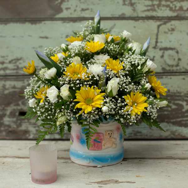 Yellow daisies and white roses arranged in a decorated ceramic vase